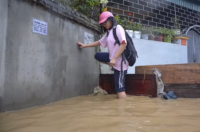 Học sinh di chuyển khó khăn trong nước lũ.