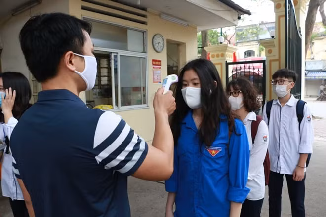 Các em học sinh xếp hàng chờ kiểm tra thân nhiệt.