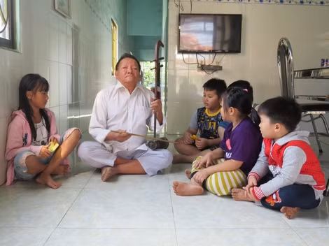 Cụ Trần Biểu đàn và hát sắc bùa cho các em nhỏ nghe để truyền lửa đam mê.