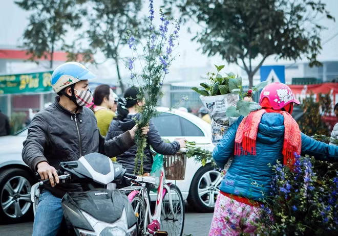 Đôi vợ chồng trẻ tranh thủ đi chợ sớm mua hoa trang trí nhà ngày Tết.