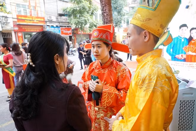 Nhân viên cửa hàng vàng trong trang phục Thần Tài hướng dẫn khách hàng.