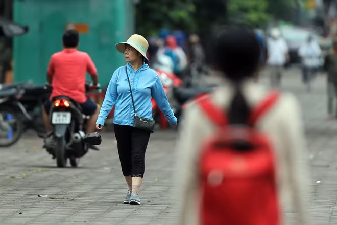 Người phụ nữ với chiếc áo chống nắng nay có thêm công dụng chống lạnh đi bộ trên phố.