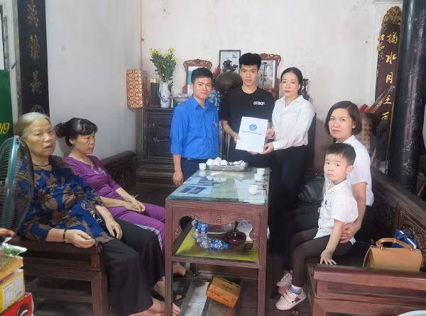 Đại diện Trung tâm truyền thông Bảo hiểm xã hội Việt Nam tặng quà, trao thr Bảo hiểm y tế cho con nữ công nhân.
