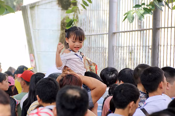 Giữa biển người trong công viên, nhiều cha mẹ buộc phải cõng con nhỏ lên vai để các bé không phải chịu cảnh chen lấn, xô đẩy