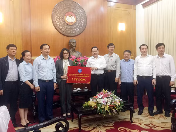 Đồng chí Nguyễn Thị Minh và CBCNV Bảo hiểm xã hội Việt Nam trao số tiền 2 tỷ đồng ủng hộ cho công tác phòng chống dịch COVID -19