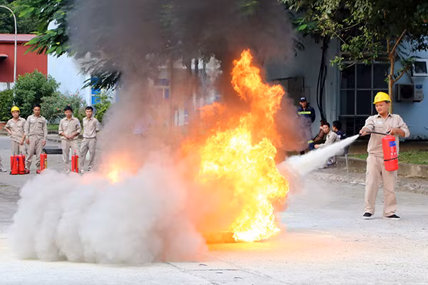 Các học viên thực hành sử dụng các bình chữa cháy dập tắt khay xăng.