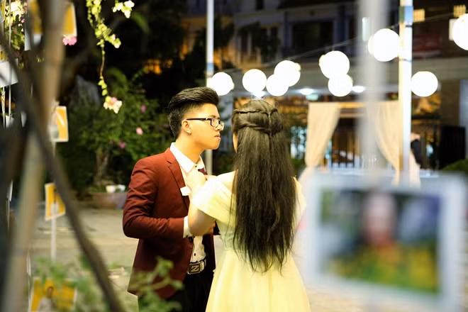 Đôi bạn trẻ vội vã chỉnh lại trang phục cho nhau trước giờ buổi lễ diễn ra.