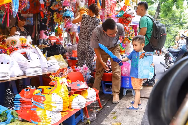 Em nhỏ theo bố mẹ dạo phố hàng Mã chọn mua đồ chơi Trung thu.