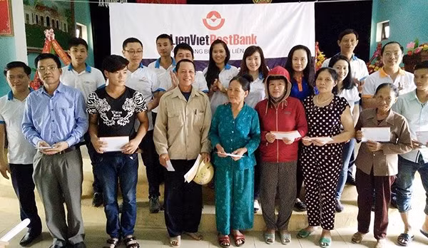 Cán bộ Ngân hàng Nhà nước Quảng Bình và Ngân hàng LienVietPostBank trao tiền hỗ trợ, chụp ảnh lưu niệm với người dân vùng lũ Quảng Bình.