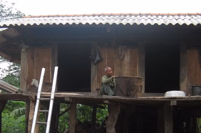 Già làng Pả Ai đan gùi bên sàn nhà.