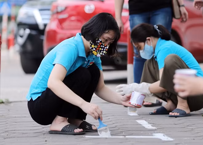 Một số giáo viên được phân nhiệm vụ đánh dấu, kẻ vạch sơn để sắp xếp vị trí cho phụ huynh khi đưa đón trẻ đảm bảo khoảng cách an toàn phòng dịch theo quy định.