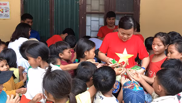 Một thành viên nhóm thiện nguyện KnD chia bánh kẹo cho các em học sinh của Trường PTDT bán trú Tiểu học và THCS số 2 Trọng Hóa.