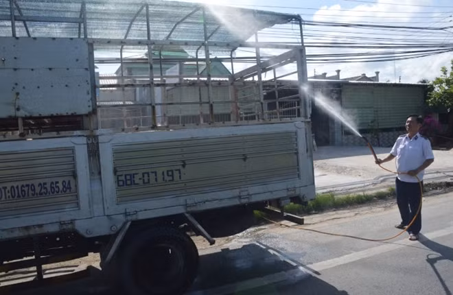 Cán bộ Thú ý tiêu độc, khử trùng và niêm phong xe chở heo trước khi di chuyển tiếp.