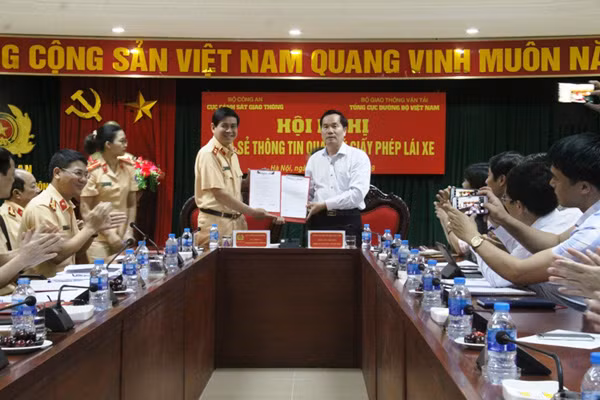 Trung tướng Vũ Đỗ Anh Dũng và đồng chí Nguyễn Văn Huyện bàn giao thông tin truy cập phần mềm.