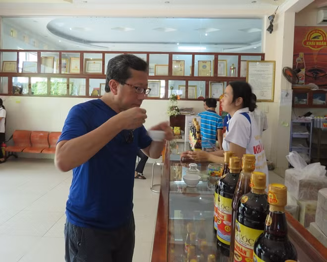 Khách du lịch nếm thử nước mắm trước khi mua tại một hãng nước mắm truyền thống ở Phú Quốc