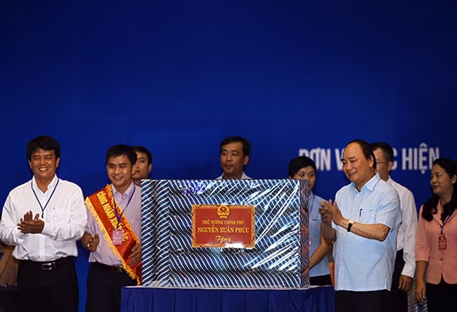 Thay mặt Chính phủ, Thủ tướng Nguyễn Xuân Phúc tặng quà cho đại diện công nhân tại các khu công nghiệp - Ảnh: VGP/Quang Hiếu.