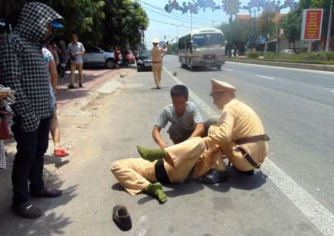 Trung úy Nguyễn Viết Tuấn nằm bất động trên đường, đang được các chiến sĩ CSGT đưa đi cấp cứu.