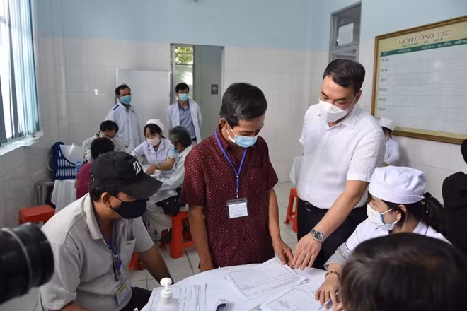 TS Nguyễn Ngô Quang (áo trắng) đang kiểm tra thủ thục của tình nguyện viên trước khi tiêm