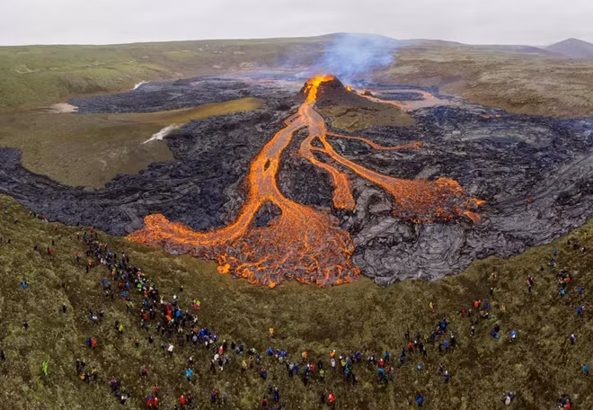 Những tay leo núi đang chiêm ngưỡng dòng dung nham phun trào từ núi lửa Fagradalsfjall, cách thủ đô Reykjavik, Iceland 40 km về phía Tây hôm 25/3. Theo các chuyên gia, khoảng 300.000 mét khối dung nham đã trào lên khỏi lòng đất. Được biết, vụ phun trào xảy ra sau nhiều tuần gia tăng hoạt động địa chấn trên bán đảo với hơn 40.000 trận động đất đã xảy ra trong vòng 4 tuần. Ảnh: Cat Gundry-Beck/Reuters.