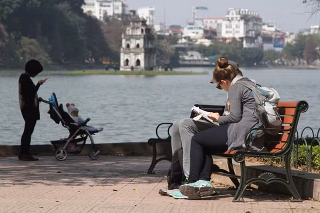 Du khách nước ngoài ngồi ven Hồ hưởng nắng mùa đông và cảm nhận không khí Tết cổ truyền Việt Nam.