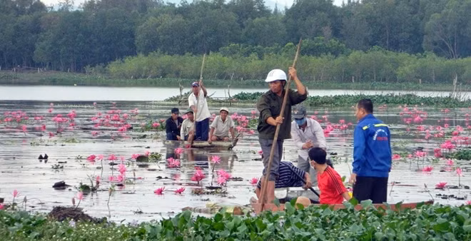 Người dân cùng cơ quan chức năng tiến hành vớt thi thể nạn nhân lên bờ.
