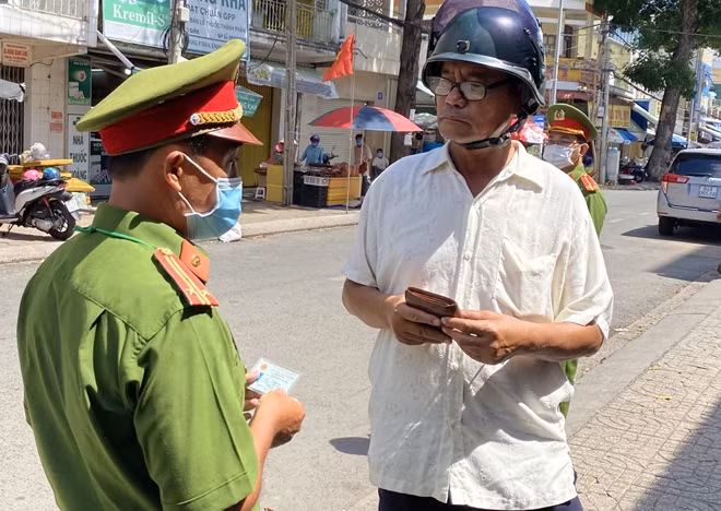 Công an phường kiểm tra, nhắc nhở người dân vi phạm việc đeo khẩu trang khi ra đường.