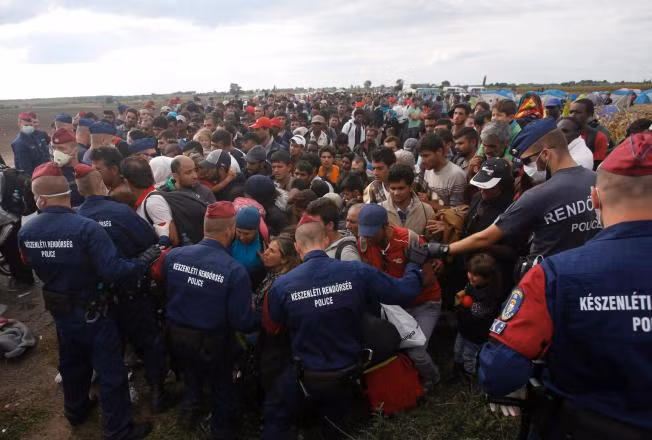 Dòng người nhập cư ở Serbia đang cố vượt qua hàng rào cảnh sát để vào biên giới Hungary. Ảnh: AP.