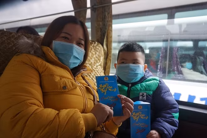 Hai mẹ con chị Trần Thị Thúy khoe được nhận “lì xì” hỗ trợ của Liên đoàn Lao động TP Đà Nẵng trên chuyến xe 0 đồng về quê đón Tết vào sáng 6/2.