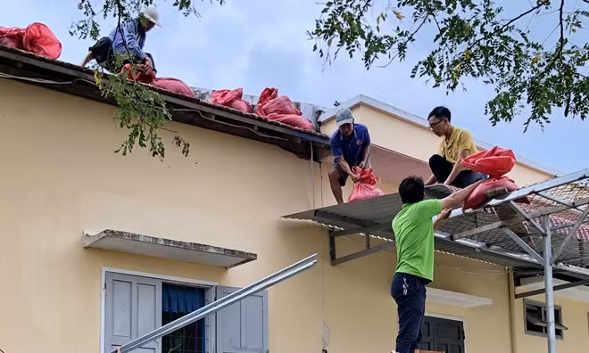 Cán bộ viên chức một công sở ở Bình Định sử dụng bao cát giằng giữ mái ngói để tránh thiệt hại do bão gây ra. Ảnh : CTV