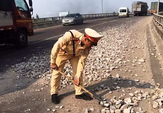 Người dân cảm phục khi chứng kiến hình ảnh CSGT Công an tỉnh Bình Định thu dọn đá dăm rơi vãi xuống mặt cầu Gành trên tuyến quốc lộ 19 Ảnh : NDCC
