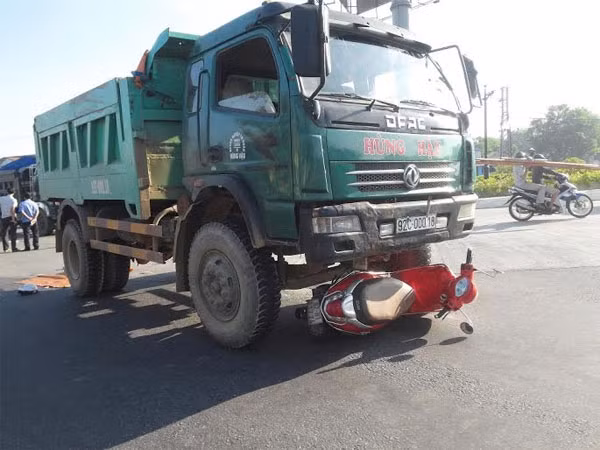 Xe máy bị kéo lê nằm gọn dưới bánh trước xe tải.
