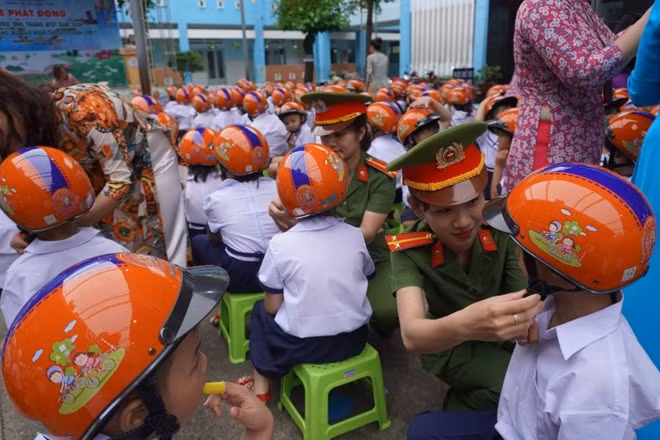 Cán bộ chiến sĩ Công an quận 12 phát mũ bảo hiểm miễn phí cho học lớp 1 trên địa bàn quận.
