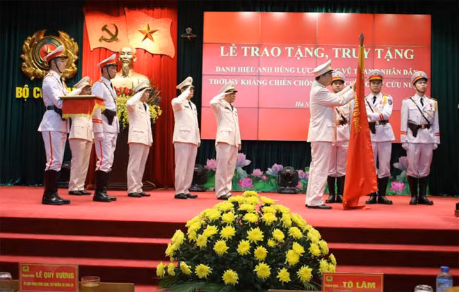 Bộ trưởng Tô Lâm gắn huy hiệu AHLLVTND lên Cờ truyền thống cho Công an Hà Nội.