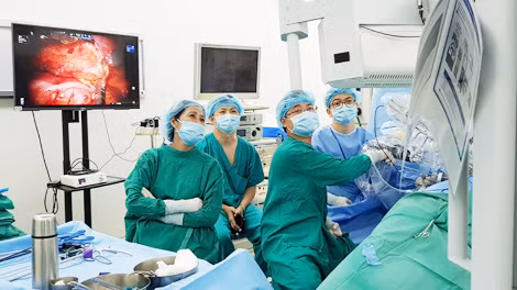 Các bác sĩ thao tác đặt các "cánh tay" robot vào cơ thể người bệnh.