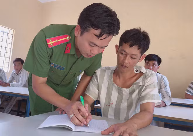 Cán bộ quản giáo nắn từng nét chữ cho phạm nhân trong giờ học.