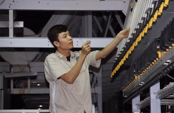 Công nhân giỏi Nguyễn Hoài Nam đang bắt sợi đưa vào cuộn.