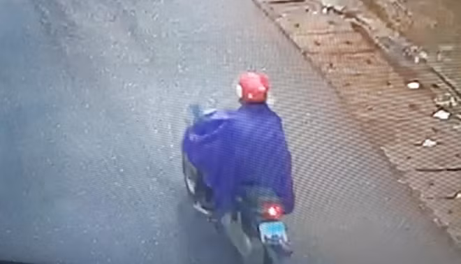 Đối tượng Phạm Văn Sỹ đi xe máy, mặc áo mưa sau khi cướp được tiền tại ngân hàng