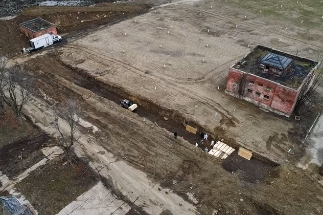 Các nhân viên mặc thiết bị bảo hộ cá nhân chôn thi thể trong một rãnh trên Đảo Hart ở quận Bronx của New York vào ngày 9/4/2020. Đảo Hart là một dải đất ở Long Island Sound từ lâu đã trở thành "nấm mồ chung" của nhiều người trong thành phố.