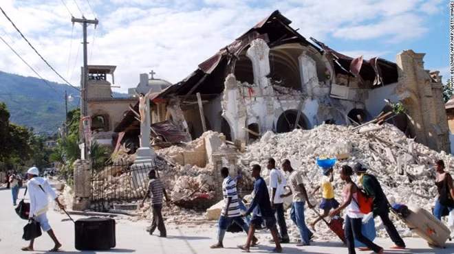 Người dân Haiti bước qua đống đổ nát từng là một nhà thờ địa phương vào ngày 12-1-2010. Ảnh Getty Images.