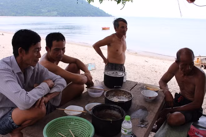 Ngư dân nghỉ ăn trưa trong một chiếc lán tạm bợ bên bờ biển, trước địa phận làng Hòa Vân