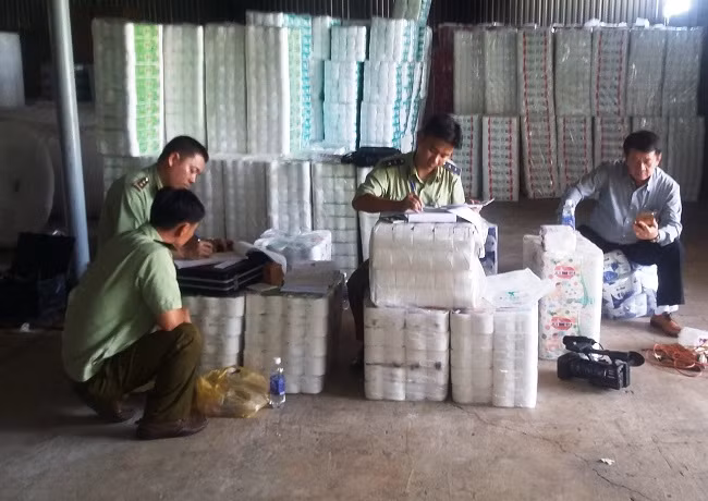 Cơ quan chức năng lập biên bản tạm giữ giấy vệ sinh giả nhãn hiệu tại cơ sở sản xuất giấy vệ sinh không phép do ông Lâm Văn Thuyền làm chủ.