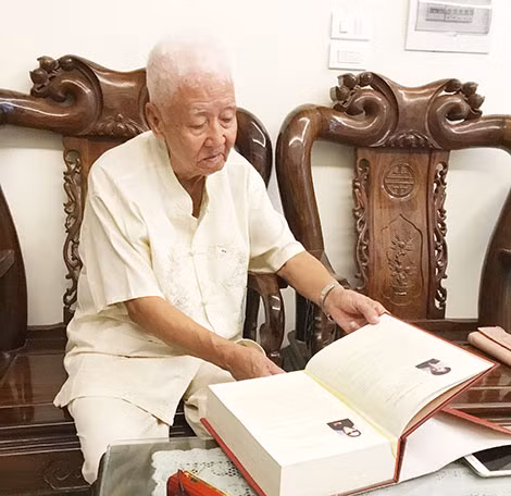 Đại tá Vũ Lễ bên quyển sách mẹ ông được truy tặng danh hiệu Mẹ Việt Nam Anh hùng.