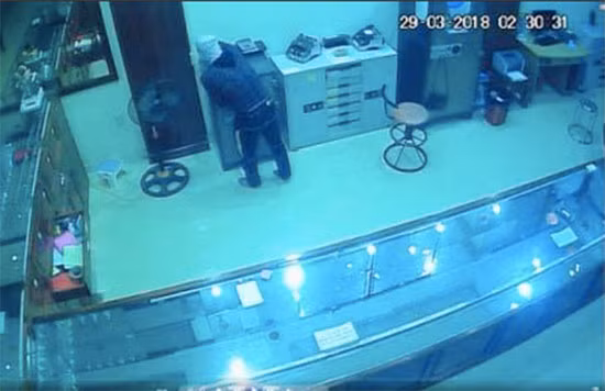 Camera an ninh ghi lại hình ảnh tên trộm cao lớn, chân đi khập khểnh, mặt bịt kín đang lúi húi vơ vàng, bạc vào túi.