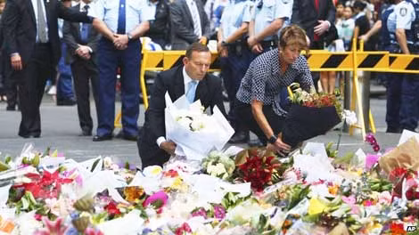 Vợ chồng Thủ tướng Australia Tony Abbott đặt vòng hoa tưởng niệm 2 nạn nhân thiệt mạng trong vụ giải cứu con tin. Ảnh: AP.