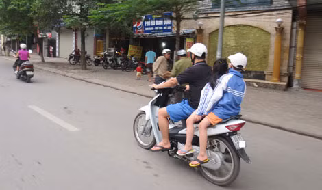 Nhiều bậc phụ huynh “quên” đội mũ bảo hiểm cho trẻ. (Ảnh chụp sáng 5/4 trên đường Lạc Long Quân).